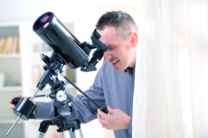 Man using reflector telescope