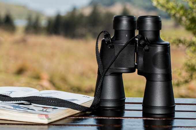 binoculars on table next to a book