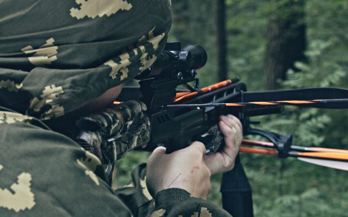 A man shooting his crossbow through a scope